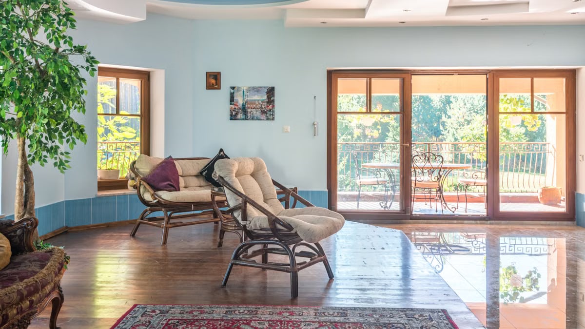 Spacious living room with modern interior and view of sunlit garden balcony.